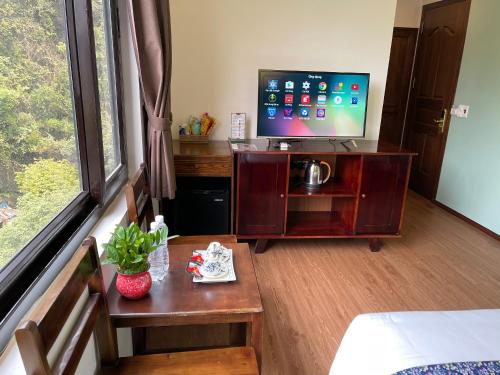 a room with a bed and a tv and a table at Tam Coc Lion Kings Hotel & Resort Ninh Binh in Ninh Binh