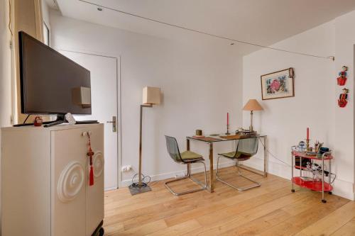 a living room with a refrigerator and a table with chairs at Historic paris charme in Paris