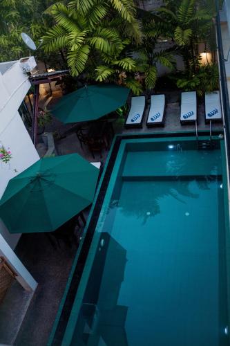 a swimming pool with two umbrellas and chairs next to it at Bienvenido Cozy Madiha in Matara