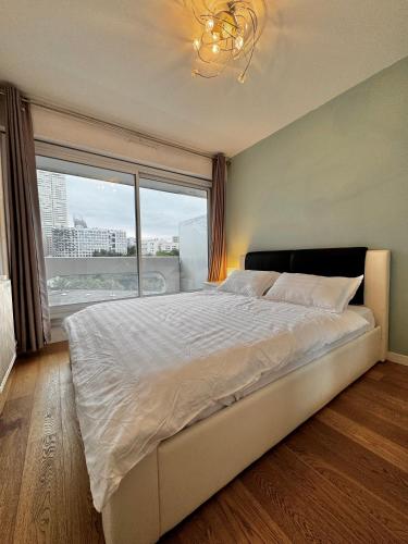 une chambre avec un grand lit avec une grande fenêtre dans l'établissement Appartement Avec Balcon Vue Sur La Défense, à Courbevoie