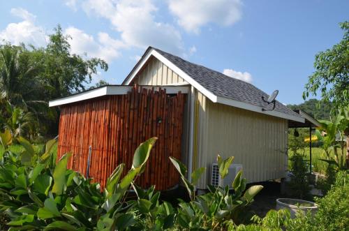 a small shed with a fence in a garden at Nok Chan Mee Na in Chom Thong