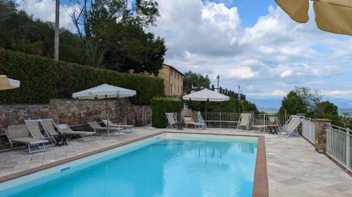 a large swimming pool with chairs and umbrellas next to at Molino del Rotone in Buti