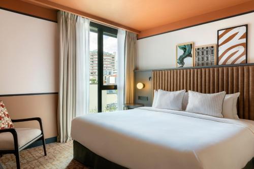 a hotel room with a large bed and a window at Le Parchamp, a Tribute Portfolio Hotel, Paris Boulogne in Boulogne-Billancourt