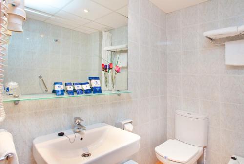 een badkamer met een wastafel, een toilet en een spiegel bij Hotel RH Riviera - Adults Only in Gandía