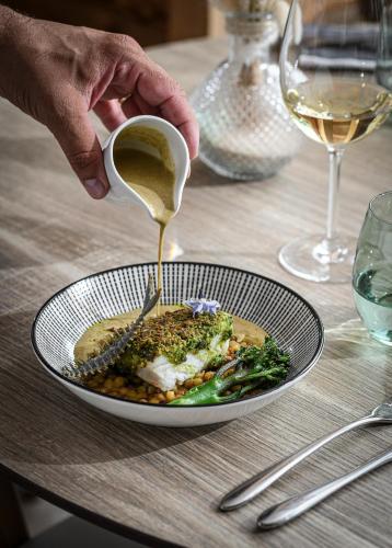 a person is pouring sauce onto a plate of food at Fleur De Neige Châtel in Châtel