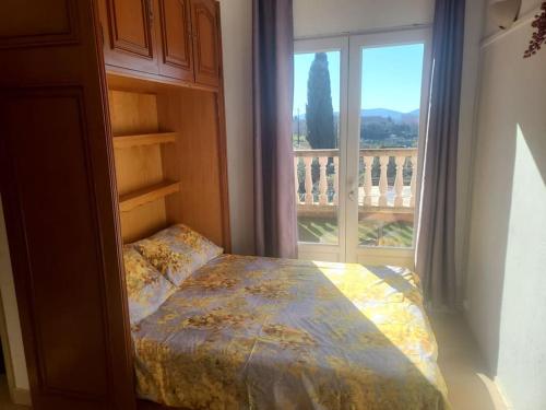 una camera da letto con un letto e una grande finestra di de 1 à 6 avec terrasse solarium, vue panoramique et parking gratuit a Grasse