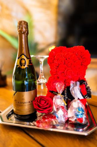 - une bouteille de champagne et des roses rouges sur un plateau dans l'établissement Le temps suspendu, Nuit sous la roche & jacuzzi, à Doué-la-Fontaine