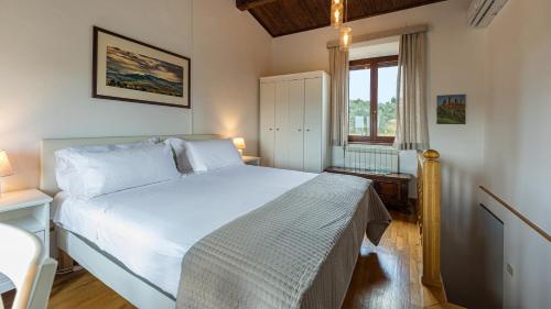 ein Schlafzimmer mit einem weißen Bett und einem Fenster in der Unterkunft VILLA PIANELLO 10, Emma Villas in Chianciano Terme