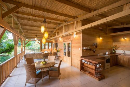 a kitchen and dining room of a log cabin with a wooden ceiling at Castara Retreats in Castara