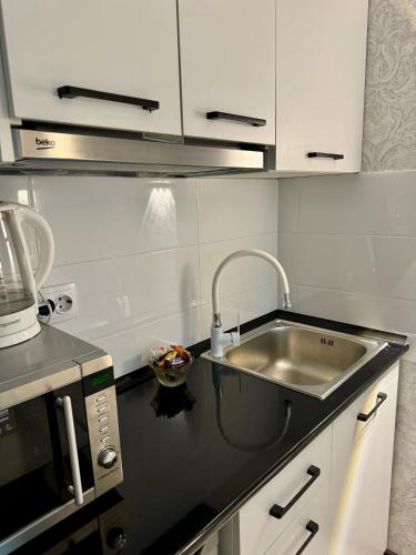 a kitchen with a sink and a microwave at Уютная комната-студия в центре Бишкека in Bishkek