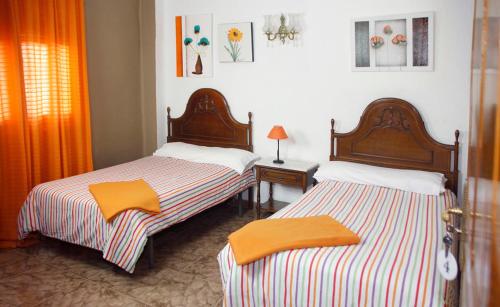 two beds in a room with orange curtains at Hernani Bardenas in Arguedas