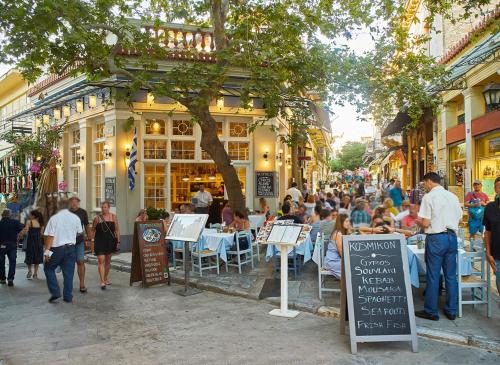 eine Gruppe von Menschen, die an Tischen in einer Straße sitzen in der Unterkunft Thissio Hideaway Suite in Athen