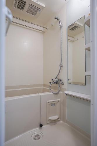 a white bathroom with a shower and a sink at Apartment Hotel 11 Namba-Minami Ebisucho-Eki Mae in Osaka