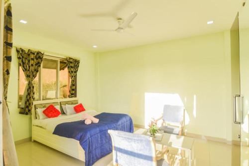 ein Schlafzimmer mit einem Bett und einem Tisch und einem Fenster in der Unterkunft 4BHK VERONICA VILLA by Welcome Stays in Lonavla