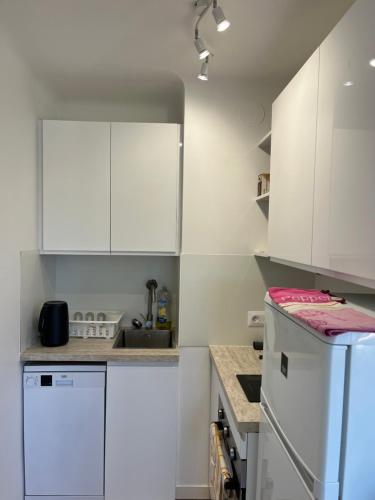une cuisine blanche avec des armoires blanches et un réfrigérateur dans l'établissement Charming studio in Cannes next to the beach, à Cannes