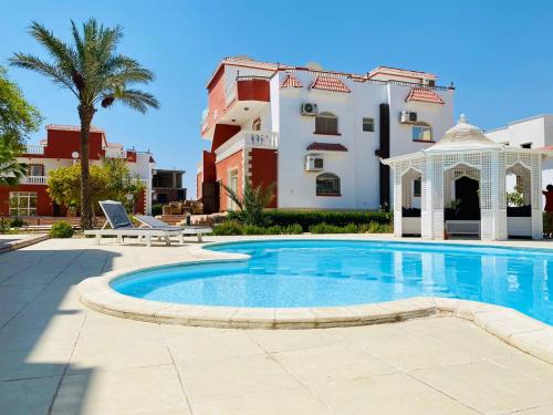 a swimming pool with a gazebo and a building at Hurghada-Magawish Villa 1 in Hurghada