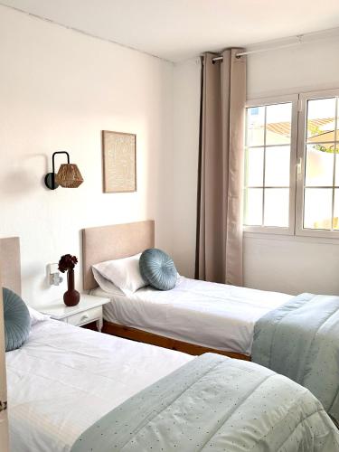 a bedroom with two beds and a window at Chalets con piscinas privadas junto al mar in Cala en Bosc