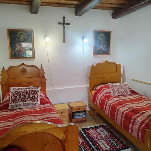 a bedroom with two beds and a cross on the wall at Zempléni Szálláshely in Fony