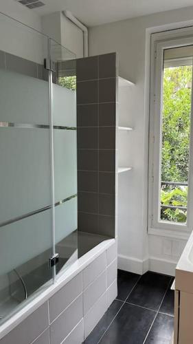 La salle de bains est pourvue d'une douche et d'une fenêtre. dans l'établissement Jolie Meulière à 15 min de Paris, à Deuil-la-Barre