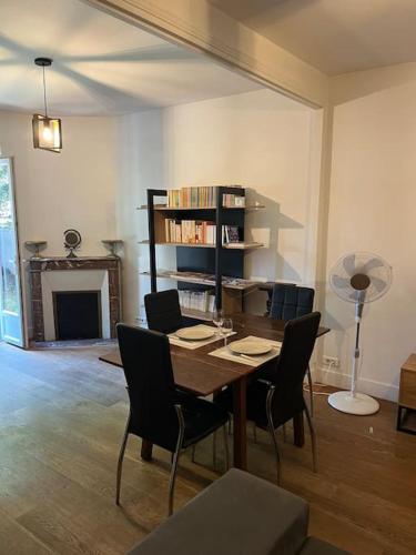 une salle à manger avec une table et des chaises et une cheminée dans l'établissement Jolie Meulière à 15 min de Paris, à Deuil-la-Barre