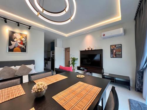 a living room with a dining table and a television at LoFF Suite River View 2 Bedroom at Kuching Riverine Resort in Kuching