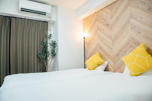 a bedroom with a large white bed with yellow pillows at Royal Heights Sakuragawa Condominium in Osaka