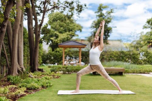 a woman doing yoga on a yoga mat in a park at Six Senses Kyoto in Kyoto