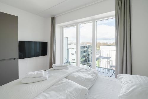 a white bedroom with a bed and a large window at Fantastic studio w balcony - 326 in Odense