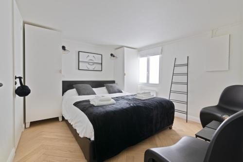 - une chambre avec un grand lit et une chaise noire dans l'établissement Élégant Appartement près du Musée du Louvre et du Jardin des Tuileries Free Netflix, à Paris