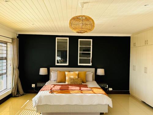 a bedroom with a large bed with a black wall at Round Robben in Langebaan