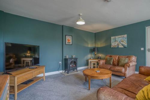 a living room with a couch and a tv at Cockle Cottage - Crabpot Cottages in Cromer