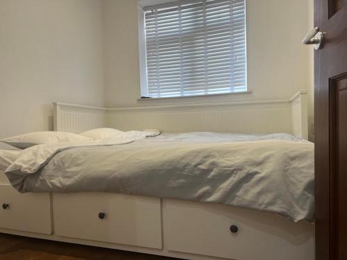 a white bed in a bedroom with a window at Self contain studio with room, double bed, kitchen in London