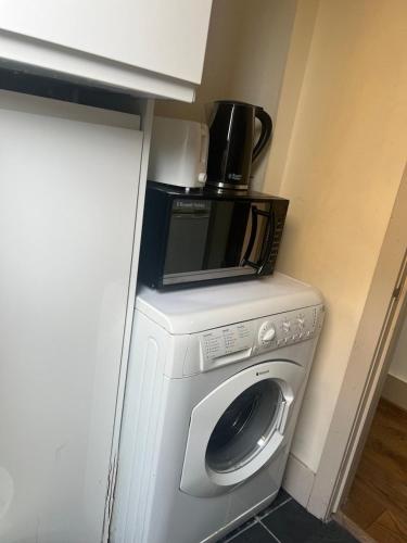 a microwave sitting on top of a washing machine at Self contain studio with room, double bed, kitchen in London