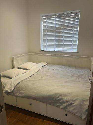 a white bed in a room with a window at Self contain studio with room, double bed, kitchen in London