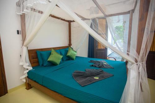 a bedroom with a bed with blue sheets and a window at Villa La Vida in Talpe