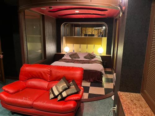 a red couch and a bed in a room at オーラリゾート四條畷 in Shijonawate