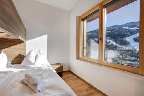 een slaapkamer met een bed en een groot raam bij Apartment SCHLADMING - Planai view in Schladming