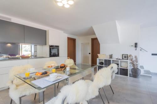 cocina con mesa de cristal y 2 sillas blancas en Harmony on the Lake by Rent All Como, en Argegno