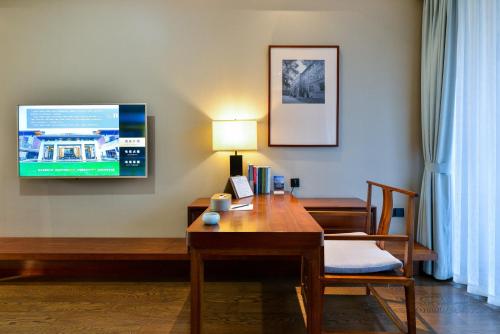 a hotel room with a desk and a tv at 海宁浙大圆正国际酒店 in Haining