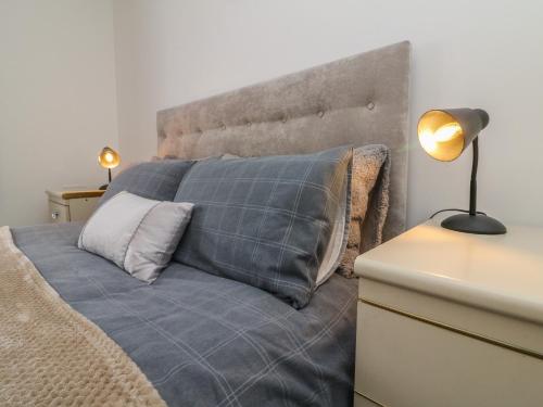 a bed with a gray blanket and a lamp on a desk at Scenic Views in High Bickington