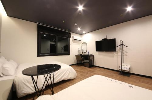 泗川市にあるSamcheonpo Ocean motelのベッド、テーブル、テレビが備わる客室です。