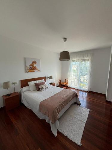 a bedroom with a large white bed and wooden floors at Casa Beatriz in Cambados
