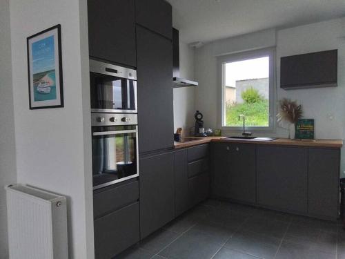 une cuisine avec des placards gris et une fenêtre dans l'établissement maison plein pied de 2023, à Quimerch