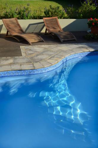 two chairs sitting next to a swimming pool at Villa Limonicella in Barrydale