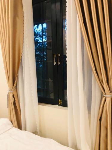 a bedroom with a window and a bed with curtains at Smiling Pine Dalat in Ấp Man Ling