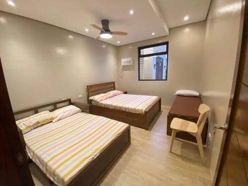 una camera da letto con due letti, una sedia e una finestra di Cristina's Holiday Home a Amadeo