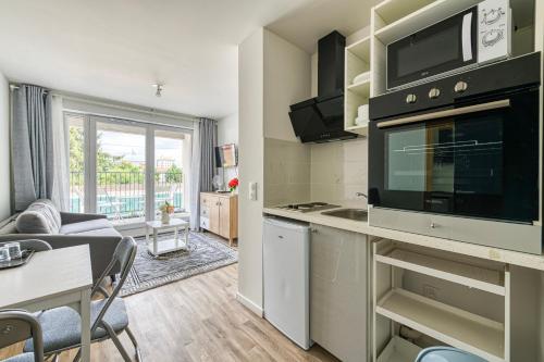 une cuisine et un salon avec un canapé et une table dans l'établissement Moulin à Vent A14 - Appt pour 4 avec balcon, à Bondy