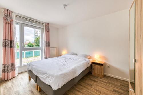 ein Schlafzimmer mit einem Bett und einem großen Fenster in der Unterkunft Moulin à Vent A14 - Appt pour 4 avec balcon in Bondy