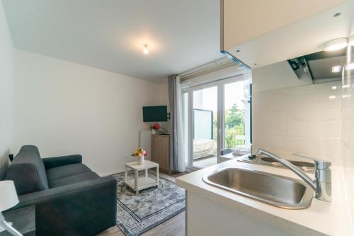 une cuisine avec un évier et un salon dans l'établissement Moulin à Vent A03 - Studio avec terrasse, à Bondy