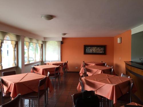 comedor con mesas y sillas y paredes de color naranja en Hotel Libertadores, en Paipa